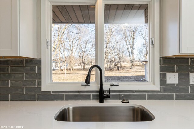 interior details featuring white cabinetry, sink, and decorative backsplash