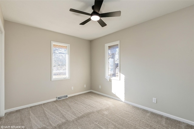 unfurnished room with light carpet, baseboards, visible vents, and a ceiling fan