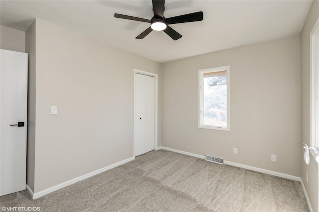 empty room with baseboards, visible vents, and light colored carpet