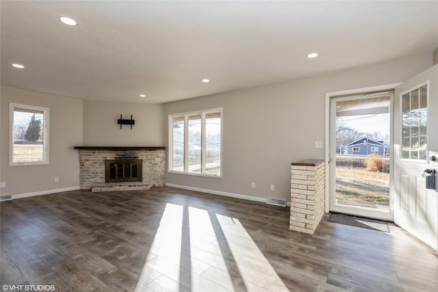 unfurnished living room featuring dark hardwood / wood-style flooring and a stone fireplace