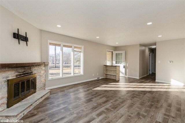 unfurnished living room featuring dark hardwood / wood-style floors and a stone fireplace