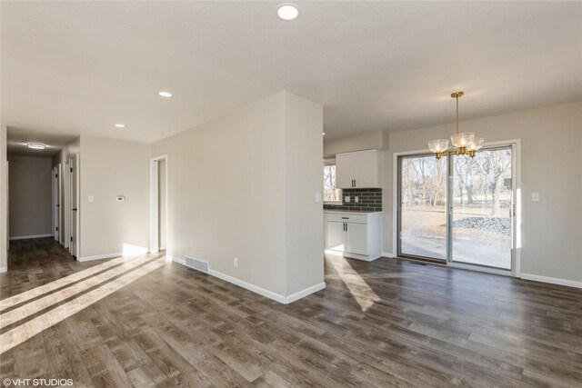 unfurnished living room featuring dark hardwood / wood-style floors and a notable chandelier