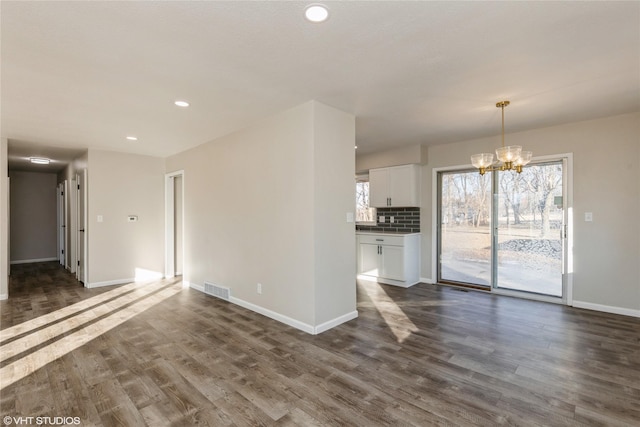 unfurnished living room featuring a chandelier, recessed lighting, visible vents, baseboards, and dark wood finished floors