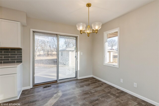 unfurnished dining area with dark hardwood / wood-style flooring, a notable chandelier, and a wealth of natural light