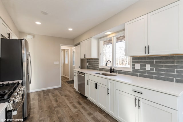 kitchen featuring appliances with stainless steel finishes, dark hardwood / wood-style floors, sink, white cabinets, and decorative backsplash