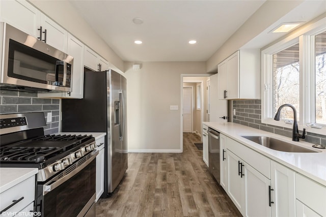 kitchen with backsplash, stainless steel appliances, sink, and white cabinets