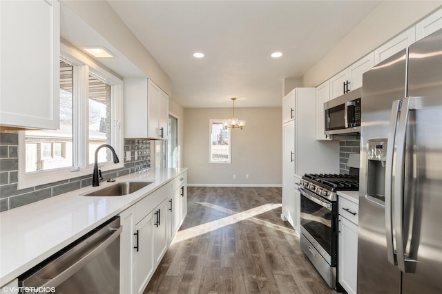 kitchen with stainless steel appliances, white cabinetry, sink, and decorative backsplash