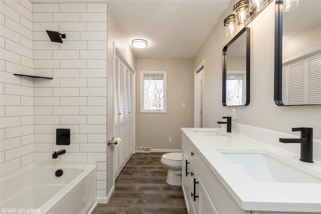 full bathroom featuring vanity, hardwood / wood-style floors, tiled shower / bath combo, and toilet