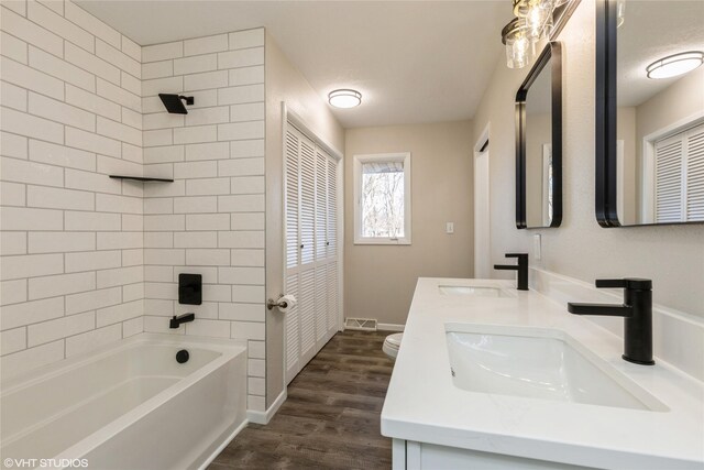 full bathroom featuring vanity, tiled shower / bath combo, wood-type flooring, and toilet