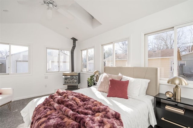 carpeted bedroom with ceiling fan, a wood stove, and vaulted ceiling