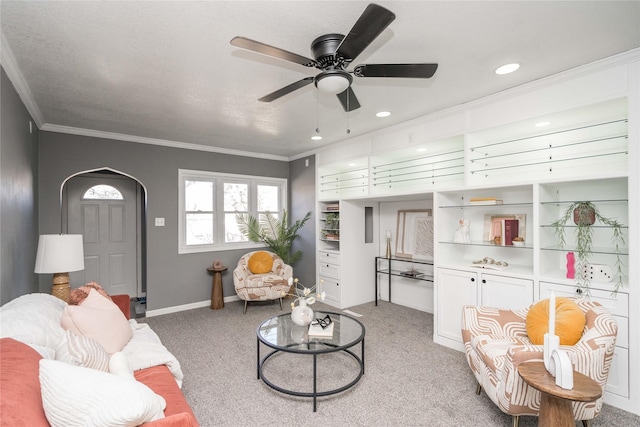 carpeted living room with ceiling fan and crown molding