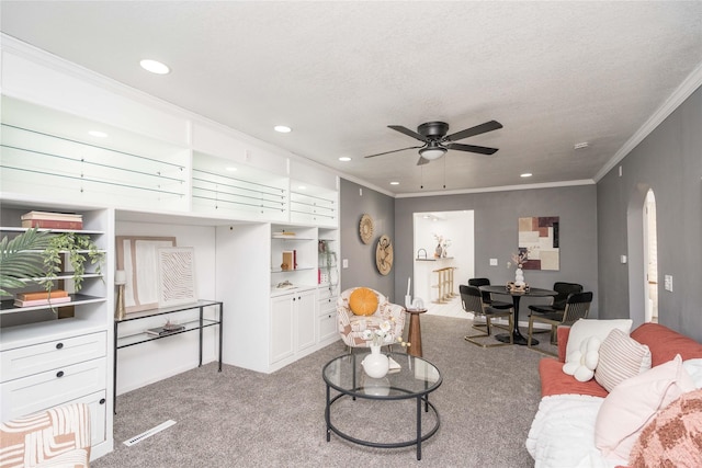 living room featuring ceiling fan, crown molding, light carpet, and a textured ceiling