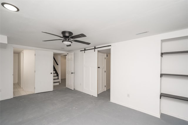 basement featuring ceiling fan and a barn door