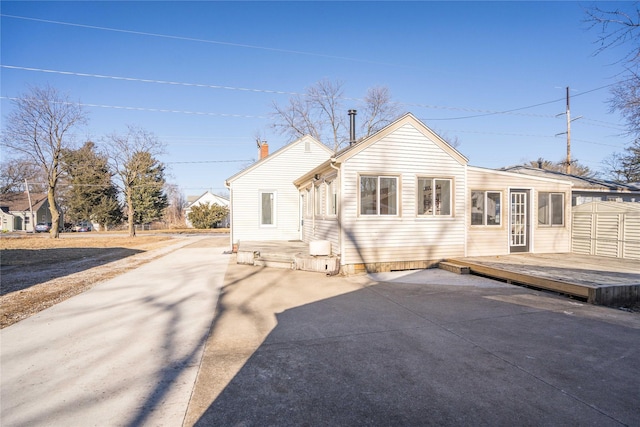 rear view of property featuring a wooden deck and a patio