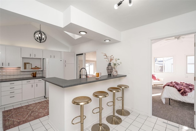 kitchen with kitchen peninsula, a breakfast bar area, tasteful backsplash, and vaulted ceiling with skylight