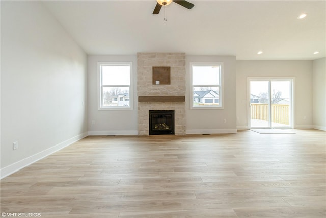 300 NW Ashley Ave, Waukee, IA 50263 - unfurnished living room featuring light wood-style flooring, a ceiling fan, a stone fireplace, and recessed lighting