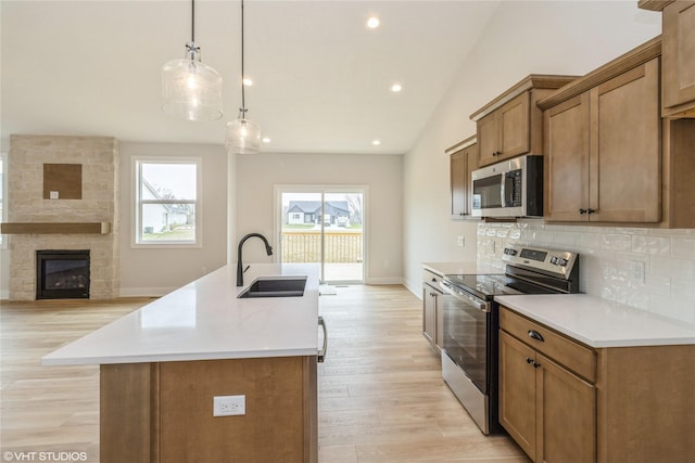 300 NW Ashley Ave, Waukee, IA 50263 - kitchen with appliances with stainless steel finishes, a sink, lofted ceiling, light wood finished floors, and decorative backsplash