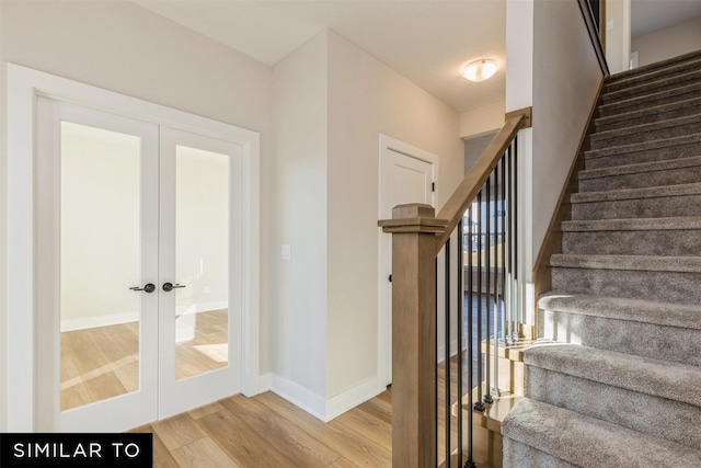 stairway with french doors and wood-type flooring