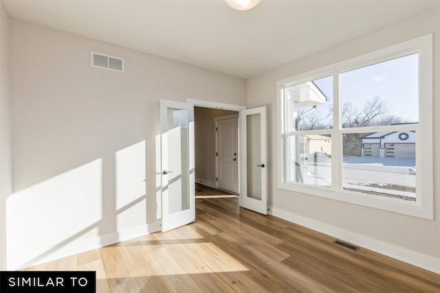 unfurnished room featuring hardwood / wood-style flooring and french doors