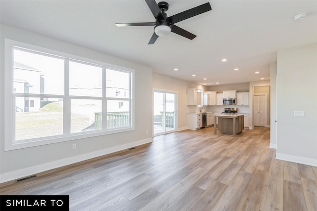 unfurnished living room featuring sink, light hardwood / wood-style flooring, and ceiling fan