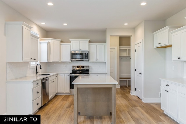 kitchen with sink, a center island, appliances with stainless steel finishes, and white cabinetry