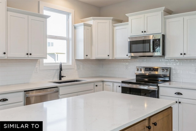 kitchen featuring sink, tasteful backsplash, white cabinetry, light stone countertops, and stainless steel appliances