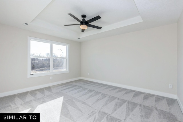 carpeted empty room with ceiling fan and a tray ceiling