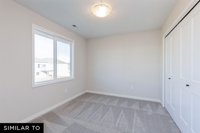 unfurnished bedroom featuring light carpet and a closet