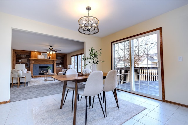 dining space with a fireplace with raised hearth, light tile patterned floors, built in shelves, and baseboards