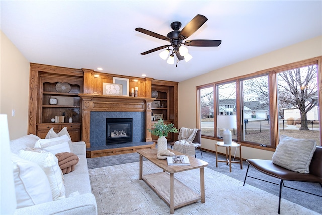 living room featuring built in features, baseboards, ceiling fan, a fireplace, and recessed lighting