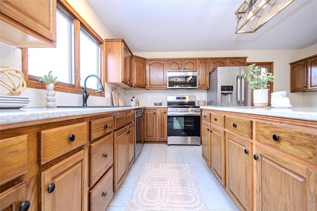 kitchen with stainless steel appliances, light countertops, a sink, and light tile patterned floors