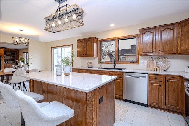 kitchen featuring a breakfast bar, a kitchen island, a sink, hanging light fixtures, and stainless steel dishwasher