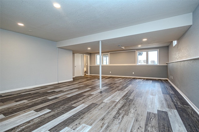 below grade area with a textured ceiling, baseboards, wood finished floors, and recessed lighting