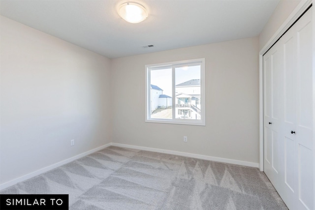 unfurnished bedroom with light colored carpet and a closet