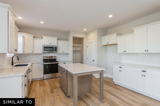 kitchen featuring appliances with stainless steel finishes, a kitchen island, white cabinetry, sink, and backsplash