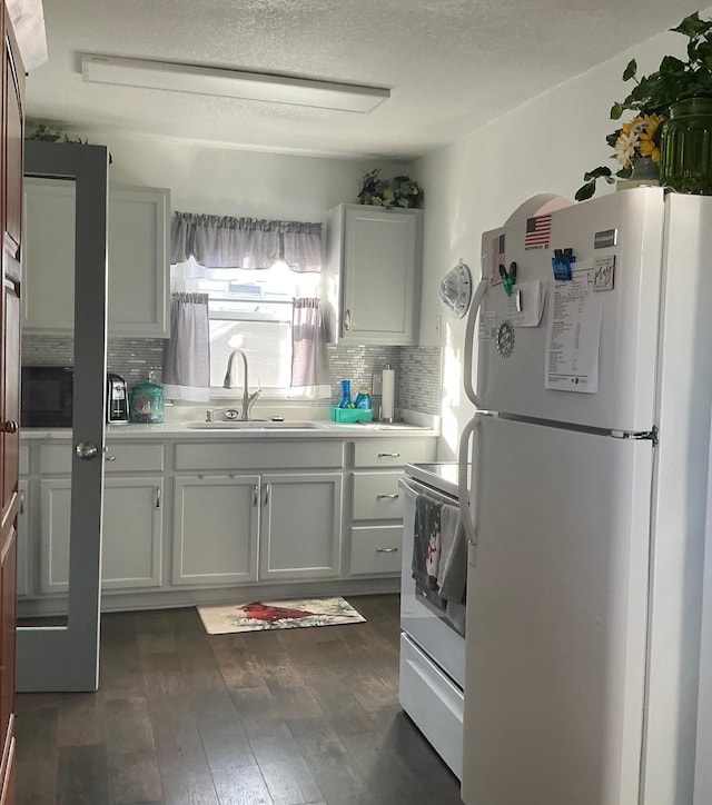 kitchen with sink, white cabinetry, dark hardwood / wood-style flooring, white appliances, and decorative backsplash