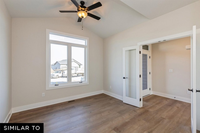 spare room featuring ceiling fan, hardwood / wood-style floors, french doors, and vaulted ceiling