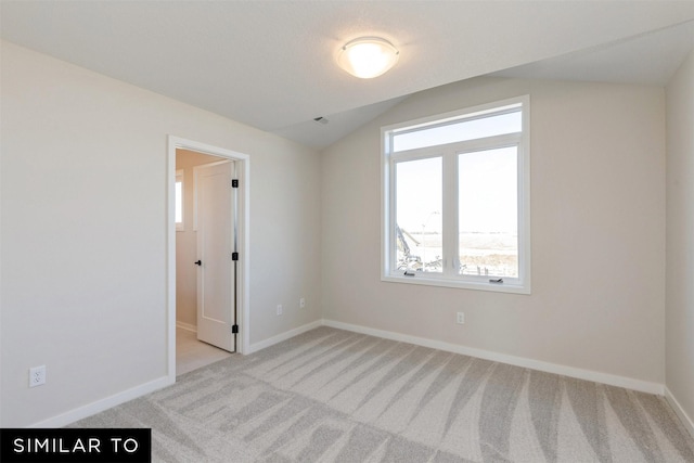 empty room with light colored carpet and lofted ceiling