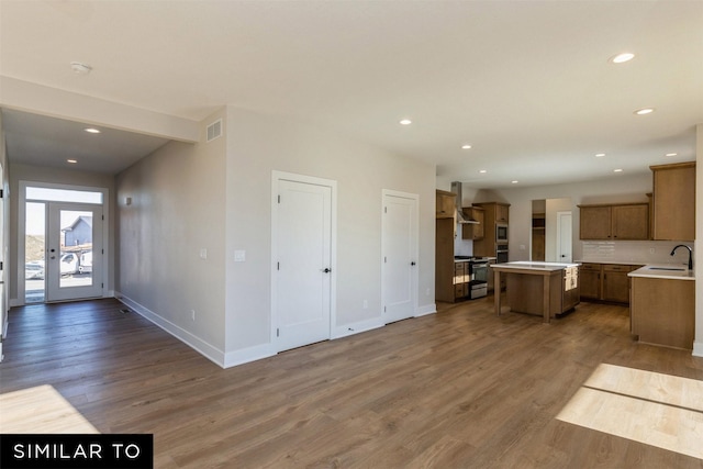 kitchen with dark hardwood / wood-style floors, appliances with stainless steel finishes, a center island, and wall chimney exhaust hood