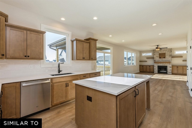 kitchen with sink, dishwasher, a kitchen island, and light hardwood / wood-style floors