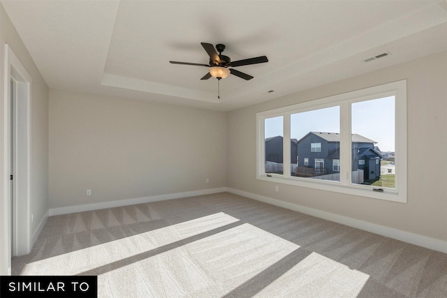 carpeted spare room featuring ceiling fan and a tray ceiling