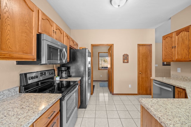 kitchen with light tile patterned floors, light stone countertops, and stainless steel appliances