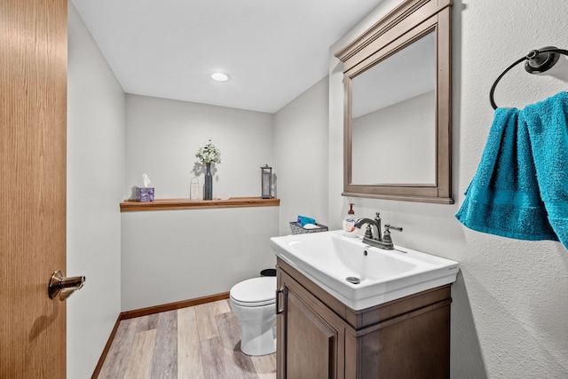 bathroom with hardwood / wood-style floors, toilet, and vanity