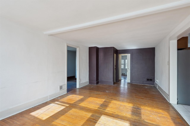 empty room with wood-type flooring and beam ceiling