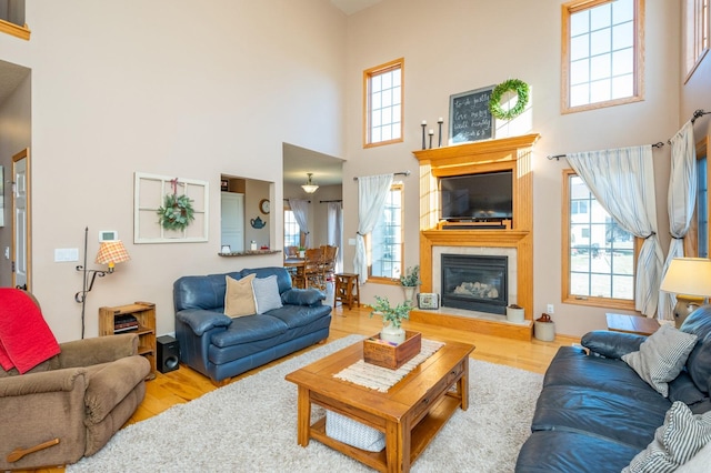 living room featuring light wood-type flooring and a towering ceiling