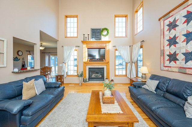 living room with light hardwood / wood-style floors and a towering ceiling