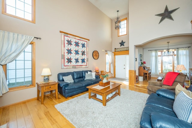 living room with a high ceiling, a chandelier, and light wood-type flooring