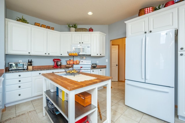 kitchen with light tile patterned floors, white appliances, and white cabinets