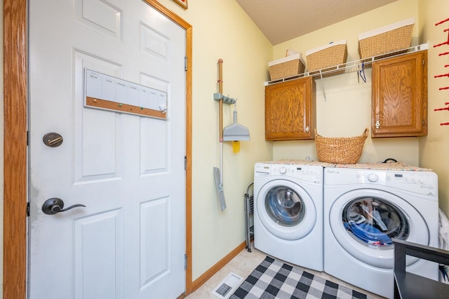 laundry room with washing machine and clothes dryer and cabinets