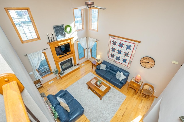 living room with ceiling fan, a high ceiling, and wood-type flooring